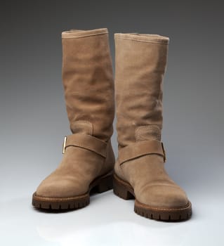 Pair of beige suede fashionable winter boots. Creative.