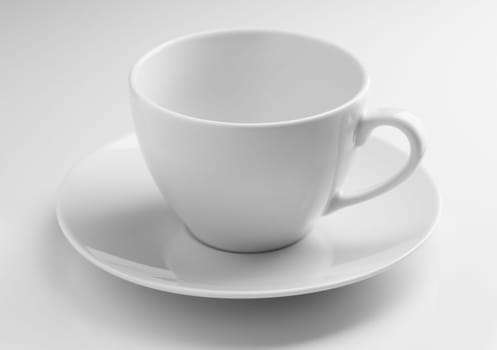 Empty ceramic cup with a saucer on a gray background