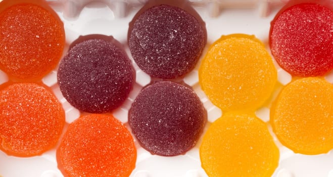 Round jelly sprinkled with sugar in a plastic box closeup.