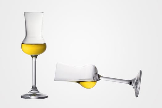 Two filled grappa glasses one levitating one is standing
