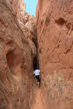 A man is hiking at Arches National Park in between huge rocks