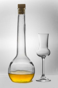 Grappa in a bottle standing next to an empty Grappa glass