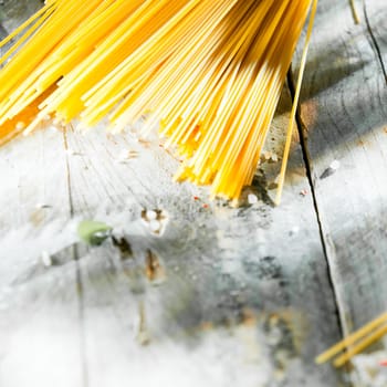 Uncooked Italian spaghetti pasta lying on an old grunge weathered picnic table with copyspace