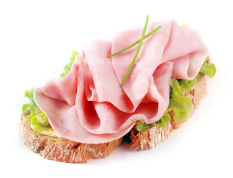 Open ham sandwich on a crusty slice of rye bread with fresh chives and lettuce over a white background