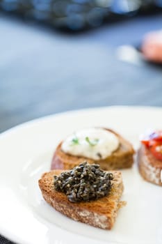 Closeup of bruschetta appetizers with savoury paste and mozzarella cheese toppings on white plate