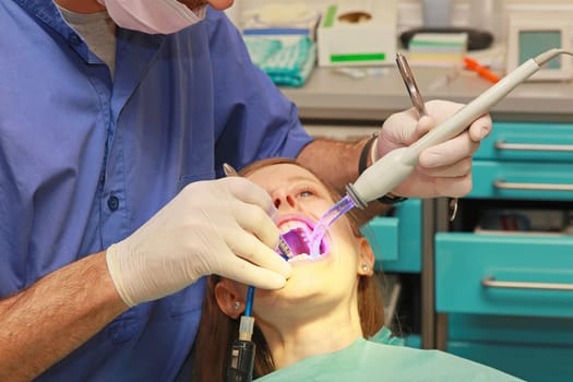 Dental curing light in girl mouth at dentist office