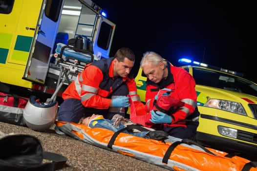 Paramedics giving firstaid to injured motorbike woman driver at night