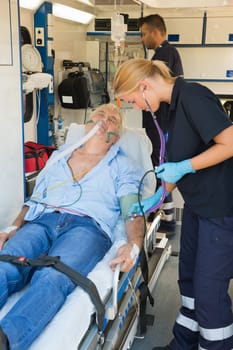 Paramedical team examining injured senior patient lying on stretcher