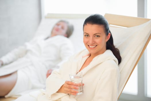 Smiling woman hold glass of water at beauty spa