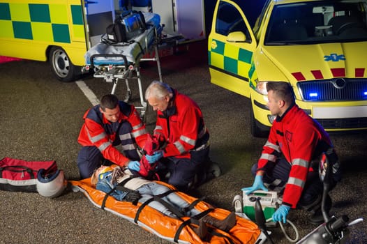 Paramedics helping injured woman motorbike driver on stretcher at night