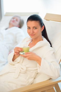 Woman enjoy coffee at beauty spa with friend in background