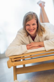 Smiling woman lying on wooden bed at beauty spa