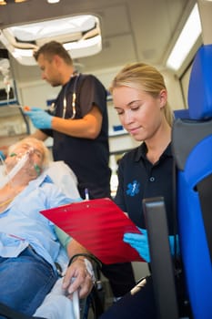 Paramedic assisting injured senior patient on stretcher in ambulance