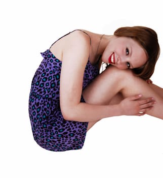 A pretty teenage girl in a blue dress with long blond hair sitting on the floor.isolated for white background..