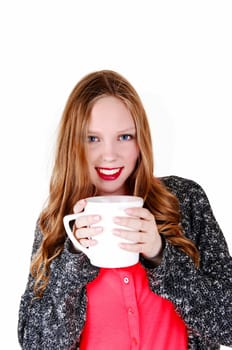 A young lovely woman standing isolated for white background holding a big.coffee mug, smiling into the camera..