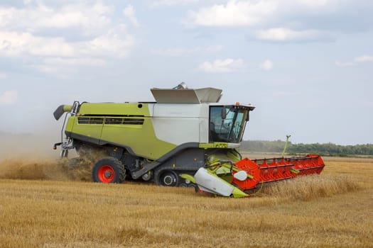 The combine mows wheat in a field