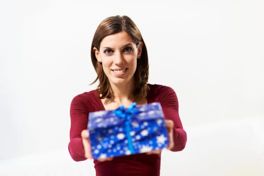 caucasian young woman showing present to the camera and smiling on white background
