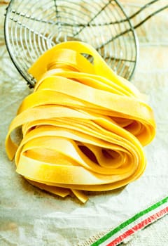 Cooked fettuccine Italian pasta lying on an old wire kitchen strainer during the preparation and cooking of a traditioal Mediterranean meal