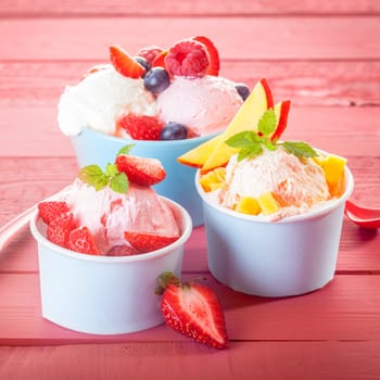 Three servings of creamy Italian ice cream with fresh fruit and assorted berries garnished with peppermint, close up square format
