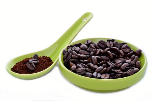 A green ceramic spoon and saucer with coffe beans on a white backgroun