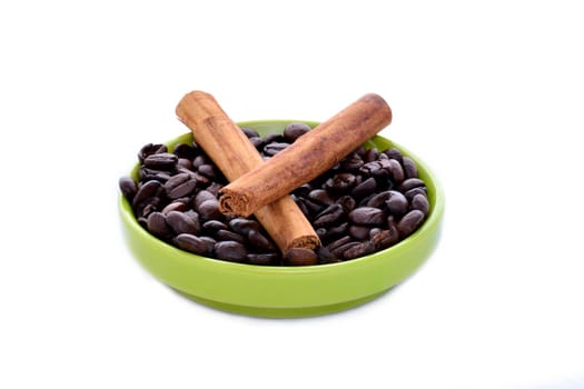 Ceramic saucer with coffee beans and cinnamon on a white background