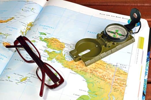 Compass, maps and glasses on a wood table