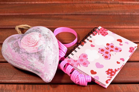 Heart with ribbon and a diary on a wood table