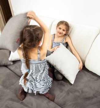 Two little girls having pillow fight on bed