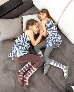 Photo of two twin girls sleeping on couch
