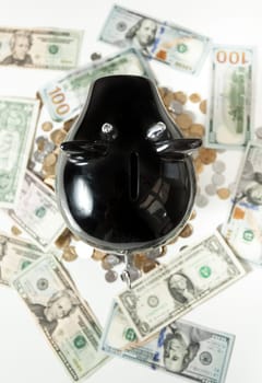 Closeup photo of black piggy bank on dollar banknotes