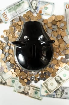 Closeup photo of black piggy bank on pile of coins