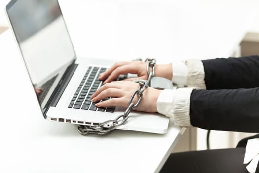 Closeup photo of businesswoman locked to laptop by chain