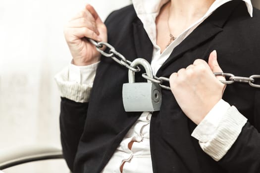 Closeup photo of businesswoman being locked by chain and padlock