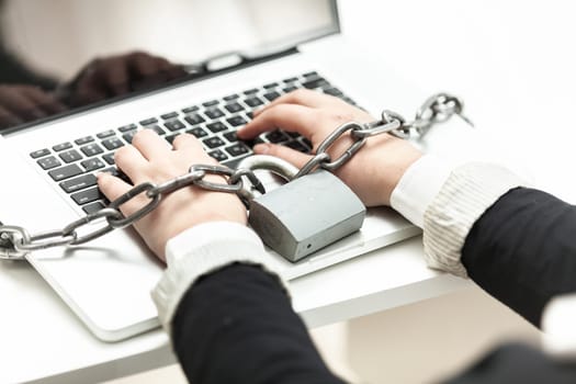 Closeup photo of woman locked in chain typing on laptop