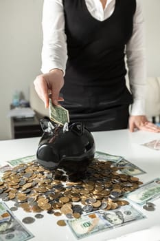 Closeup photo of woman inserting dollar in pig moneybox