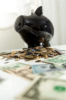 Photo of black piggy bank standing on pile of money