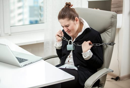 Portrait of tied businesswoman tearing apart metal chained