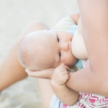Mother breastfeeding baby on the beach