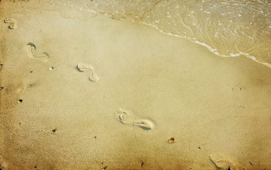 Vintage photo of footsteps in the sand at the beach