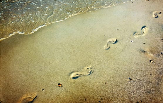 Vintage photo of footsteps in the sand at the beach