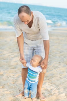 Father is helping his son to make first steps outdoor