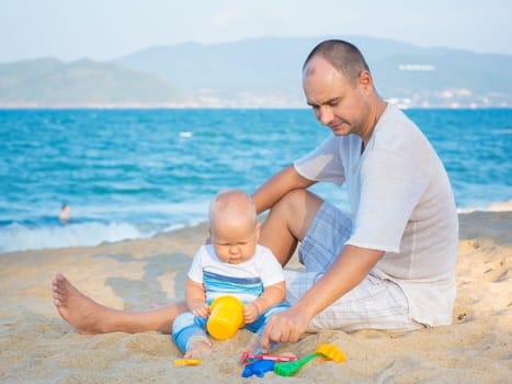 Father and baby are playing beach toys