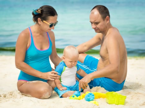 Parents and baby playing together on the beach