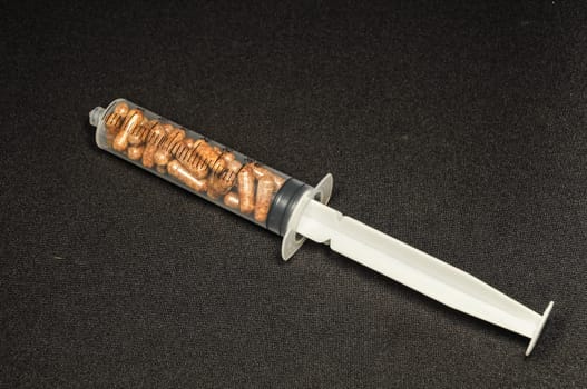Medical Syringe Full of Pill Drugs on a Black Background