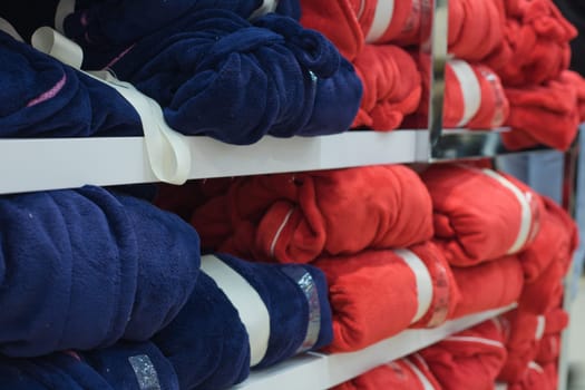 Piles of multicolored cotton clothing on the shelves of a fashion shop