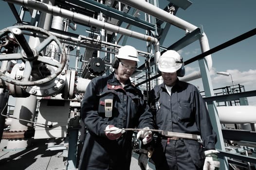 two oil and gas workers inside large oil and gas refinery, petrochemical industry