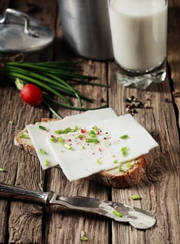 Preparing a delicious goats milk cheese sandwich topped with chopped fresh assorted herbs on a slice of rye bread in a rustic kitchen