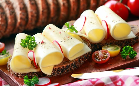 Gouda cheese rolls on an open vegetarian sandwich with radish, parsley and cherry tomatoes for a delicious lunchtime snack