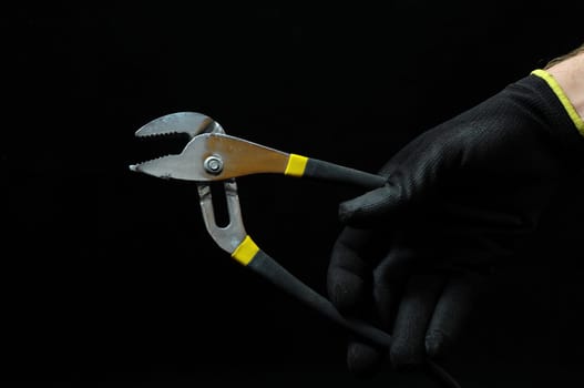Pliers and a Hand on a Black Background
