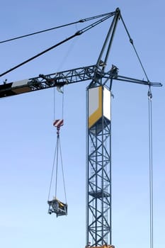 The photograph of a lifting crane with a hanging load.